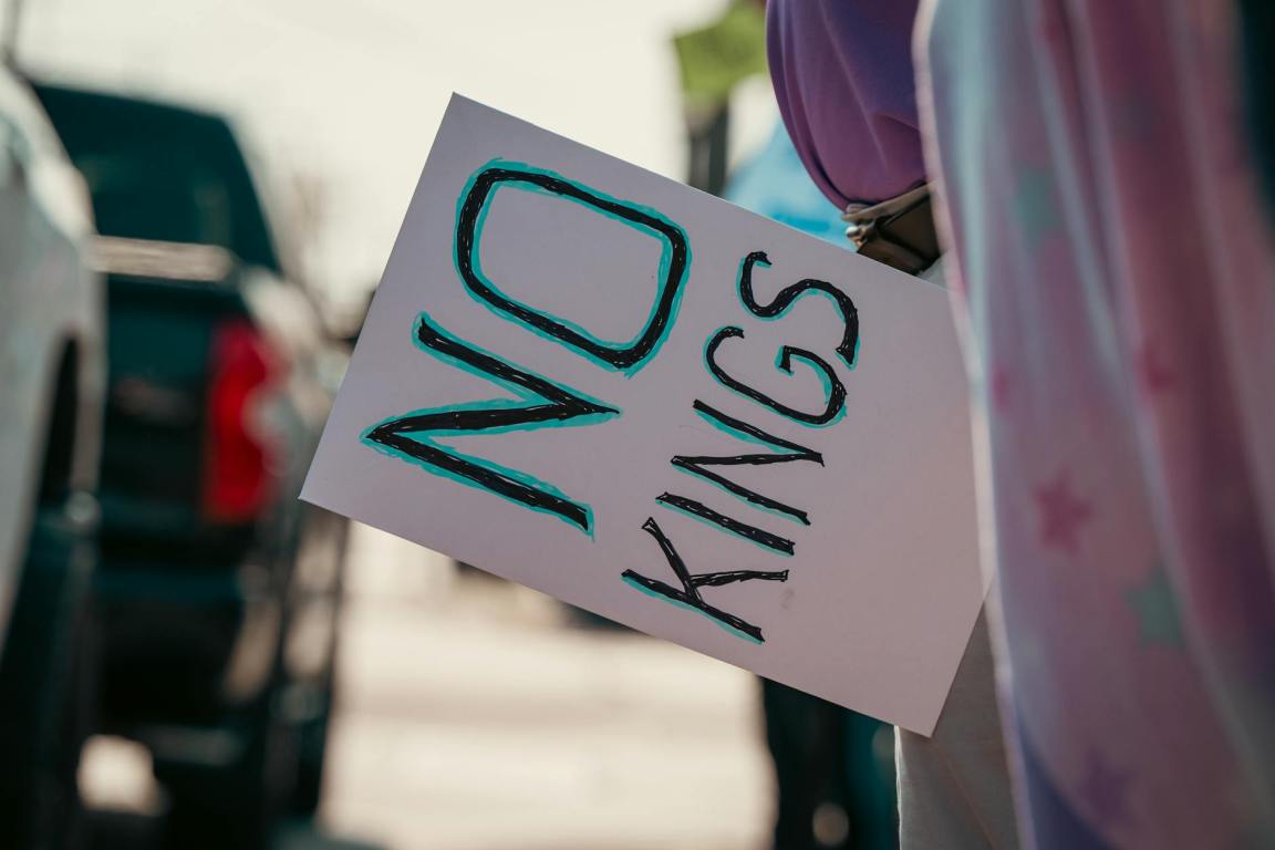 protest sign reading no kings held on street