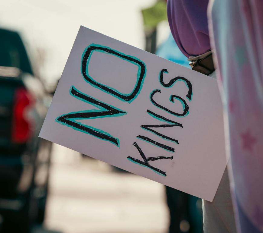 protest sign reading no kings held on street