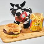 burger and fries with toy cow on wooden board